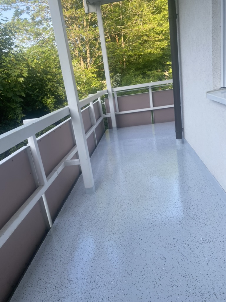 Balkon mit heller Bodenbeschichtung und farblich abgestimmtem Geländer