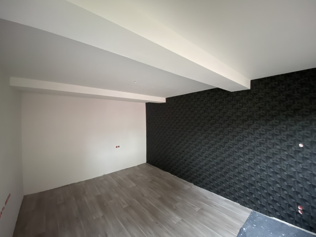 Wohnraum mit geometrischer Mustertapete als dunkler Akzentwand