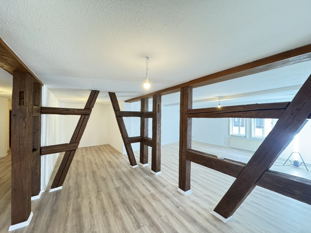 Wohnraum mit sichtbarem Fachwerk, hellen Wänden und Holzbodenoptik